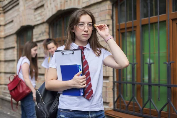 十几岁的女大学生穿着白色T恤 戴着眼镜 站在室外摆姿势 背景砖建筑 女生群体 开始上课 回到大学 复制空间 — 图库照片
