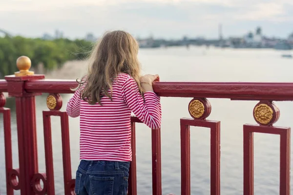 金发碧眼的孩子站在河上的人行天桥上 女孩梦想着观看和欣赏水面上的落日 — 图库照片