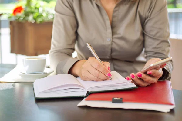 Empresaria Escribiendo Cuaderno Negocios Con Teléfono Inteligente Cerca Mujer Sentada — Foto de Stock