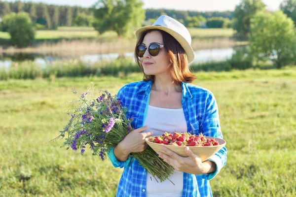 Kvinnlig Bonde Med Skål Med Nyplockade Jordgubbar Och Blombukett Natur — Stockfoto