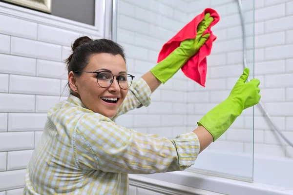 バスルームで掃除をしている女性 マイクロファイバーで洗濯布で女性の洗浄研磨シャワーガラス — ストック写真