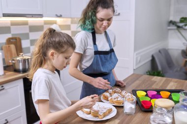 Çocuklar pastaları beyaz şeker tozuyla süslüyor.