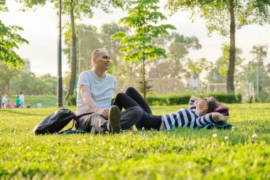 Orta yaşlı çift yoga minderinde oturuyor, kadın ve erkek rahatlatıcı içme suyu hakkında konuşuyorlar. Aktif sağlıklı yaşam tarzı, ilişki, spor, olgun insanlarda spor