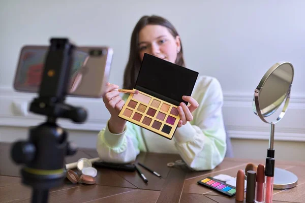 Teenage girl, beauty blogger filming video for channel blog, showing eye shadow. Telling and showing makeup and does invisible natural makeup. Beauty, technology, communication teenagers online