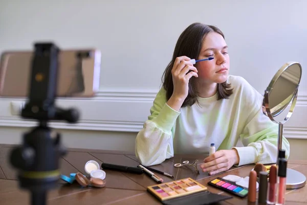 Teenage girl, beauty blogger filming video for channel blog, showing mascara. Telling and showing makeup and does invisible natural makeup. Beauty, technology, communication teenagers online