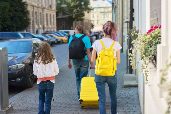 Niños dos niñas hijas y padre, turistas caminando con mochilas y maleta —  Fotos de Stock