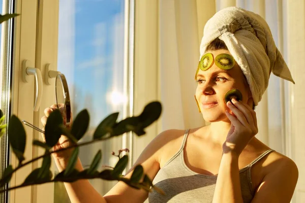 Smilende Ung Vakker Kvinne Nærheten Vinduet Med Naturlig Hjemmelaget Ansiktsmaske – stockfoto