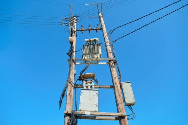Tahta direklerde elektrik trafosu, mavi gökyüzü arkaplanı..