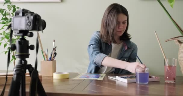 Artiste adolescente, dessine et enregistre sur caméra vidéo pour son blog. Slider tracking shot — Video