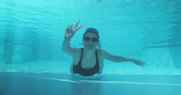 在蓝色室外游泳池里游泳的少年女子运动员，看着镜头，手举着手势，取得了胜利 — 图库视频影像