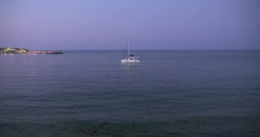 Yunanistan, Girit, 09-09-2019. Deniz akşam manzarası. Deniz koyunda küçük bir yat, iskele ve deniz feneri ışıkları.
