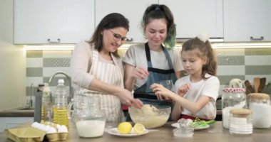 Annem iki kızına mutfakta kek pişirmeyi öğretiyor.