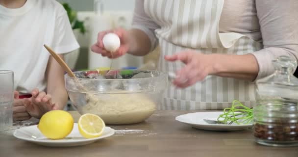 Madre e hija del niño juntos en la cocina casera amasando masa en un tazón, primer plano — Vídeo de stock