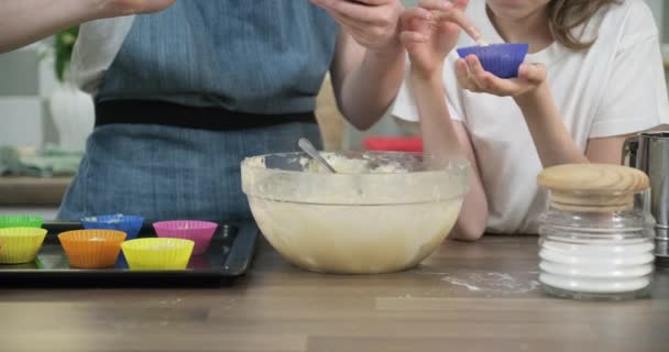 Gros plan des mains des enfants versant de la pâte dans des cupcakes . — Video