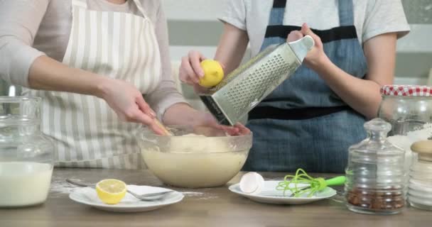 Las manos de las madres y las hijas preparan magdalenas, amasan la masa con la ralladura de limón tarta, de cerca — Vídeo de stock