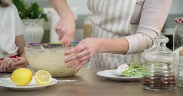 Mother and daughter child together at home kitchen kneading dough in bowl, close-up — Stock Video