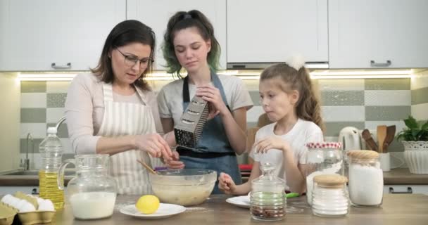 Matka učí své dvě dcery vařit muffiny doma v kuchyni — Stock video