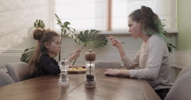 Les enfants deux filles mangent le déjeuner assis à table dans la cuisine de la maison, la nourriture maison — Video