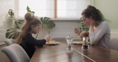 Çocuklar, iki kız öğle yemeğini evde mutfak masasında yer, ev yapımı yemekler yer.