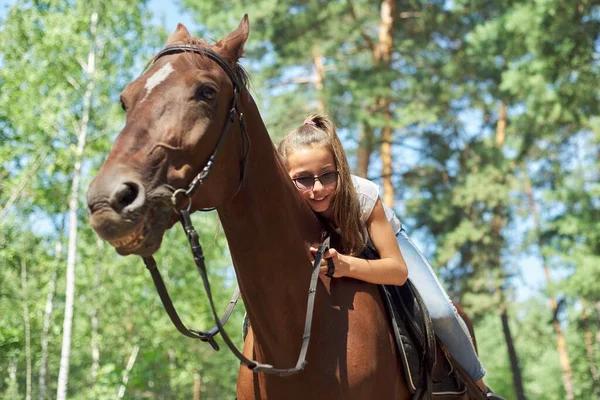 Dziewczyna dziecko jazda konna, latem jazda konna w lesie, dziewczyna z miłością przytulił konia — Zdjęcie stockowe