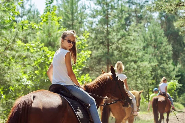 Adolescente menina montando um cavalo marrom, cavalgando para as pessoas no parque — Fotografia de Stock