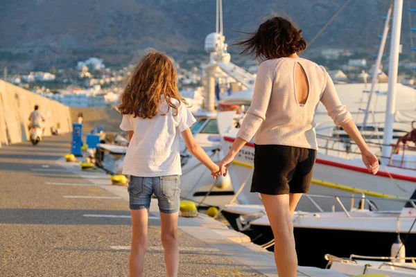 Счастливая мать и дочь, идущие вместе, держась за руки вдоль берега — стоковое фото