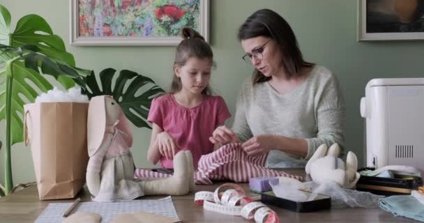 Mãe feliz e filha costurando juntos brinquedo boneca coelho em casa — Vídeo de Stock