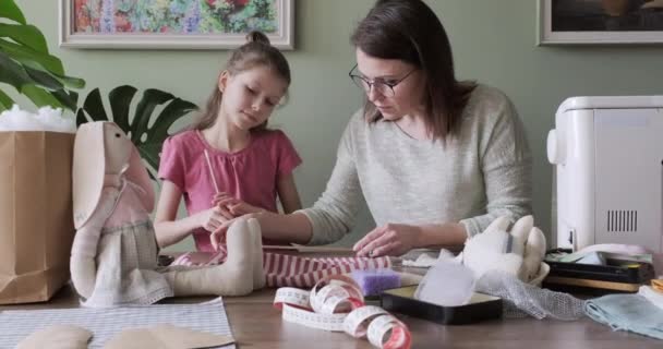 Glückliche Mutter und Tochter nähen Spielzeug-Hasenpuppe zu Hause zusammen — Stockvideo