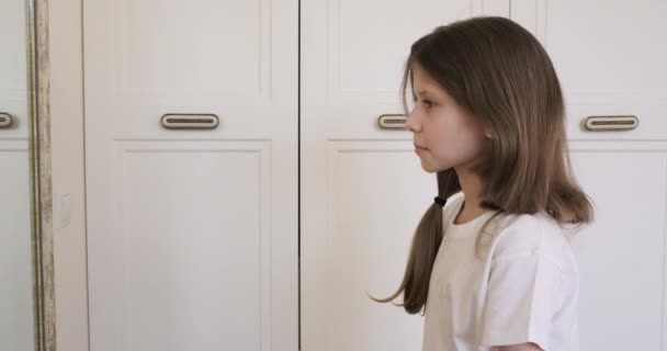 Menina engraçada criança cortando o cabelo com tesoura sentado em casa na frente de um espelho. Beleza, penteado, emoções, crianças — Vídeo de Stock