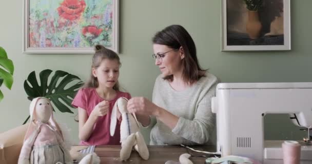 Glückliche Mutter und Tochter nähen Spielzeug-Hasenpuppe zu Hause zusammen — Stockvideo