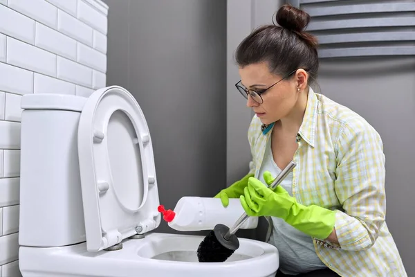 Casalinga che lava e disinfetta servizi igienici, in guanti con detersivo e spazzola — Foto Stock
