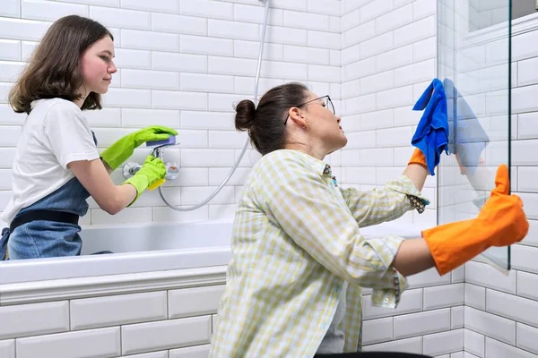 Семья мать и дочь-подросток вместе убирают дома в ванной комнате — стоковое фото