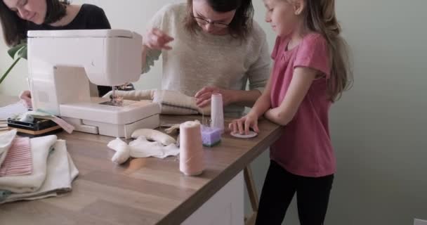 Moeder en twee dochters naaien speelgoed aan elkaar op naaimachine thuis — Stockvideo