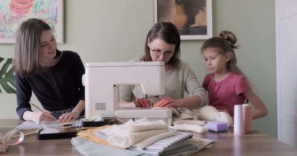 Moeder en twee dochters naaien speelgoed aan elkaar op naaimachine thuis — Stockvideo