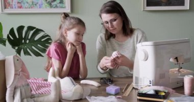 Anne ve kızı evde birlikte dikiş dikiyorlar. 