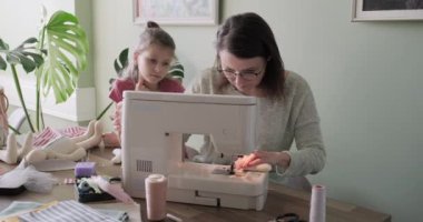 Anne ve kız evde dikiş makinesiyle dikiş dikiyorlar.