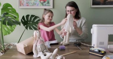 Mutlu anne ve kız evde oyuncak bebek dikiyorlar.