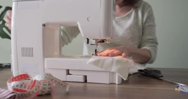 Volwassen vrouw naait op een naaimachine die thuis aan tafel zit — Stockvideo