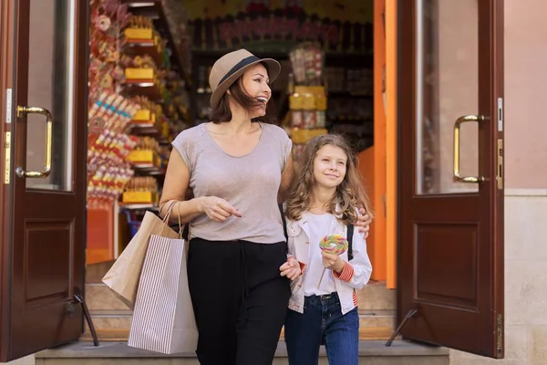 Lächelnde Mutter und Tochter laufen aus Karamellbonbonladen — Stockfoto