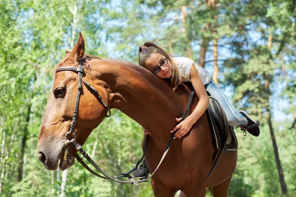 Girl child riding horse, summer horse ride in the forest, girl lovingly hugged horse — Stock Photo, Image