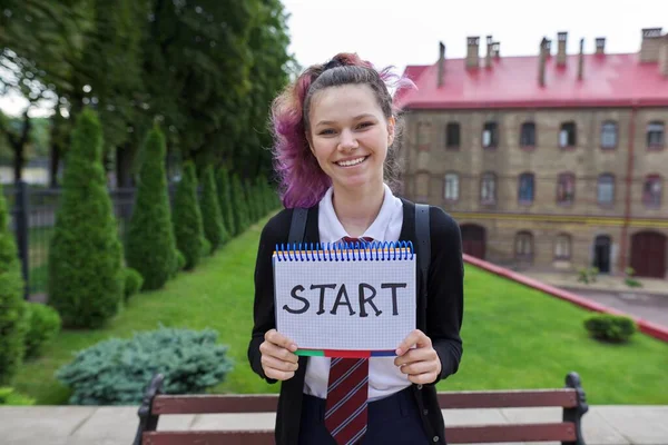 Teenager girl holding notepad with word start. Zpátky do školy, zpátky na vysokou. — Stock fotografie