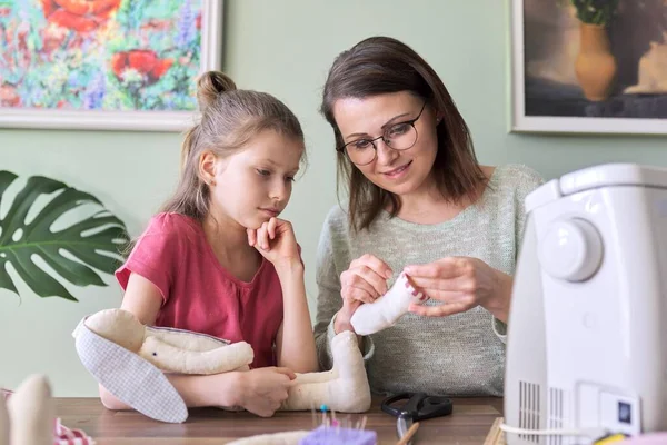 Mutlu anne ve kız evde oyuncak bebek dikiyorlar. — Stok fotoğraf