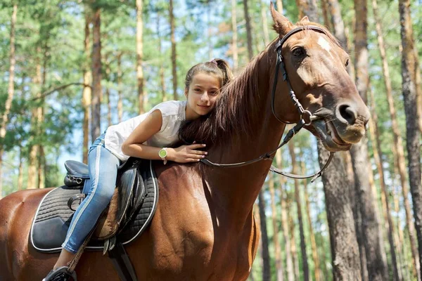 Flicka barn ridning häst, sommar häst rida i skogen, flicka kärleksfullt kramas häst — Stockfoto