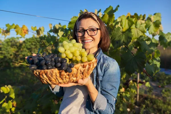 Portret van een gelukkige vrouw met een mand druiven — Stockfoto