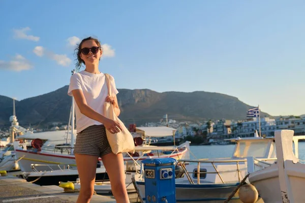 Красива дівчина-підліток, що йде уздовж морської набережної, пірс з яхтами — стокове фото
