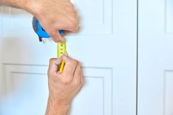 Монтаж нового шафи, майстер планує місце кріплення дверних ручок — стокове фото