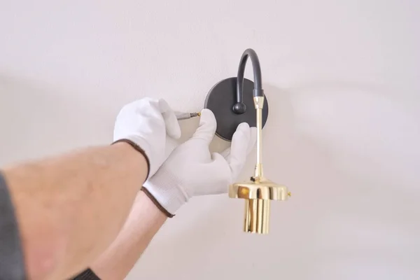 Close-up hands of electrician installing wall lamp — Stock Photo, Image