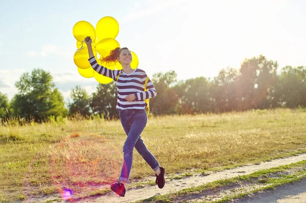 Glad tonåring flicka med ballonger som springer och hoppar längs landsvägen — Stockfoto
