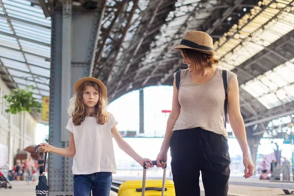 Mutlu anne ve kız çocuğu tren istasyonunda bavulla birlikte yürüyor. — Stok fotoğraf