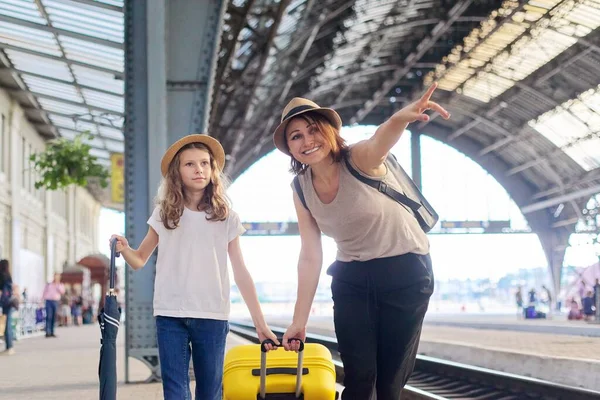 Szczęśliwa matka i córka dziecko spacerują razem na dworcu kolejowym z walizką — Zdjęcie stockowe
